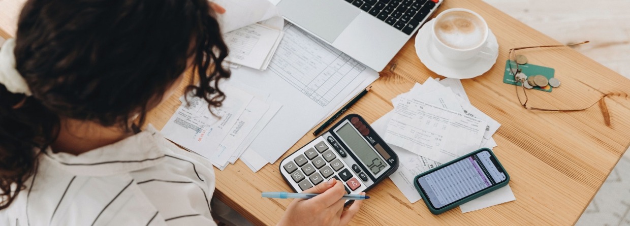 Bovenaanzicht van een vrouw die thuis in de keuken werkt met financiële papieren