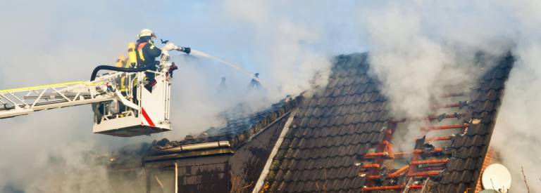 Brandweerman is brand aan het blussen van een huis