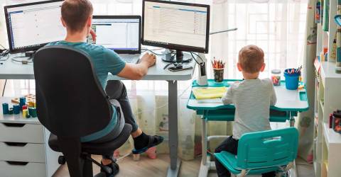 Vader met kind thuis aan het werken achter bureau