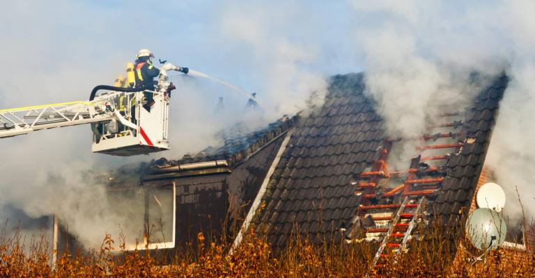 Brandweerman is brand aan het blussen van een huis