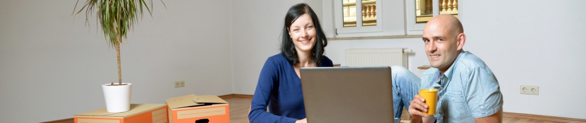 Man en vrouw zitten op de grond met verhuisdozen